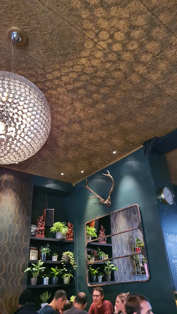Détail de l'intérieur du Volt Bar : plafond en liège, suspension boule à facettes et miroir cuivré entouré de plantes.