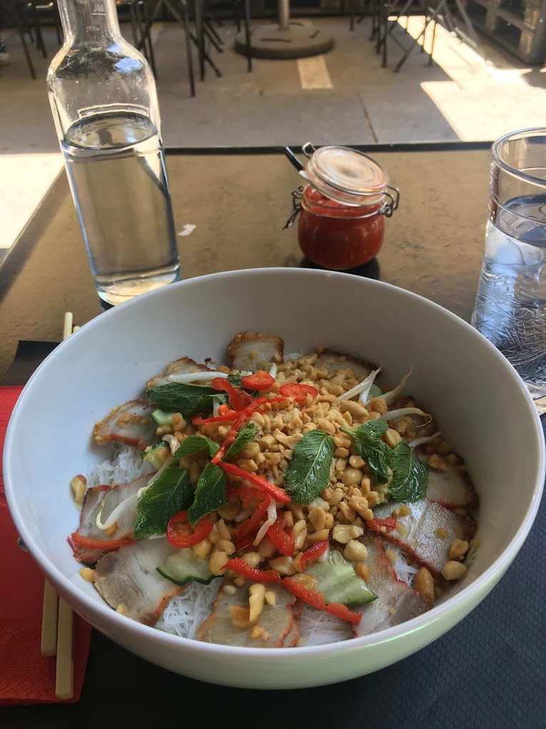 Bol de vermicelles au porc et aux herbes servi en terrasse du Volt Bar, avec carafe et verre d'eau.